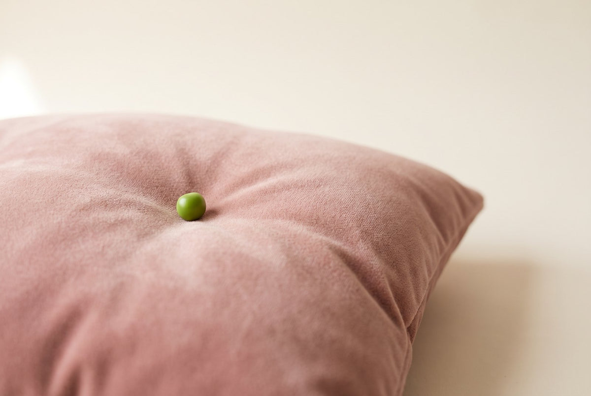 Un petit pois posé sur un coussin en velours rose poudré : un tout petit point dur qui suffit à gêner, comme le noyau d'un cor au pied
